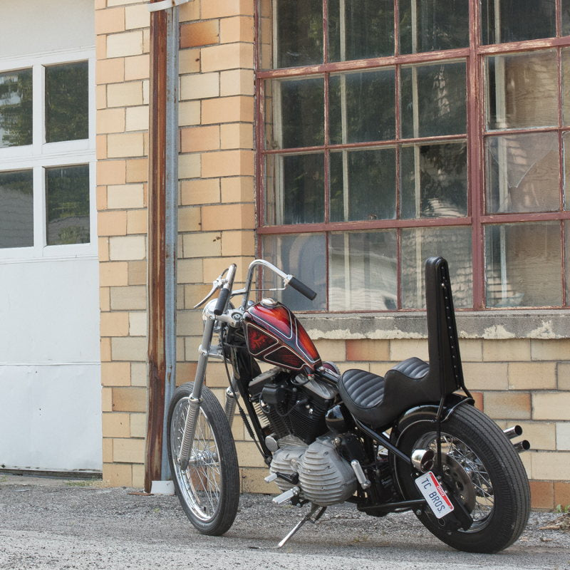 A Moto Iron® 2.1gal Narrow Sportster Frisco Style Bobber Gas Tank Harley Davidson motorcycle, parked in front of a building.
