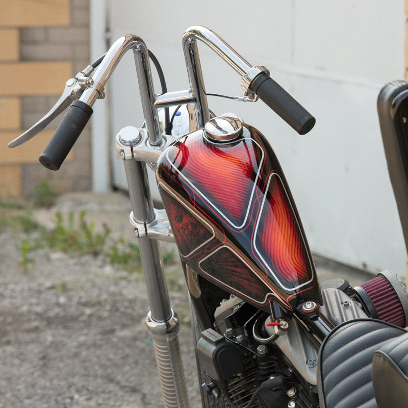 A Moto Iron® 2.1gal Narrow Sportster Frisco Style Bobber Gas Tank motorcycle parked in front of a building.