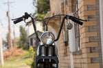 A motorcycle with TC Bros. 7/8" Ape Hanger Handlebars - 12" Black Powdercoated is parked in front of a house.