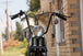 A motorcycle with TC Bros. 7/8" Ape Hanger Handlebars - 12" Black Powdercoated is parked in front of a house.