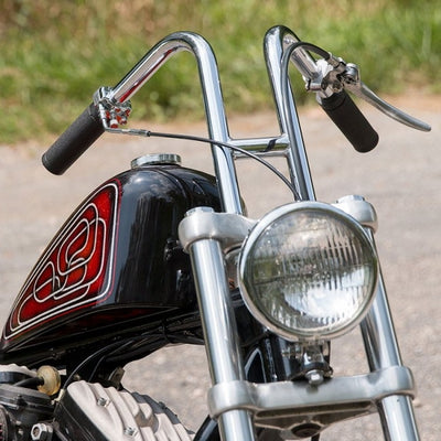 The front end of a TC Bros. motorcycle, with chrome accents, is parked on the road.