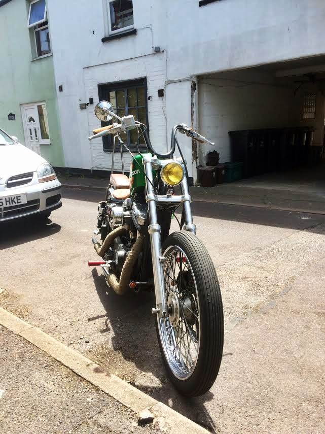 A black motorcycle with TC Bros. 1" Bootlegger handlebars parked on the side of a street.