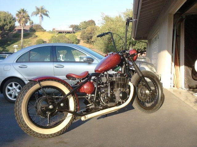 A red Moto Iron® 3.3 Gal. Mustang Tank parked in front of a garage.