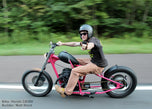A man riding a Moto Iron® 2.1 Gal. Narrow Alien Chopper Gas Tank on a road.