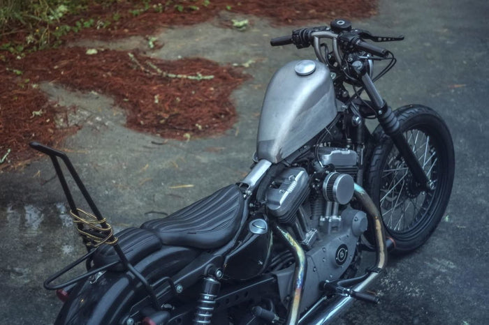 A black Moto Iron® motorcycle parked on a gravel road, with gas cap provisions for a Moto Iron® Frisco Sportster EFI Tank 2007-UP - 2.5gal fuel pump and tank.