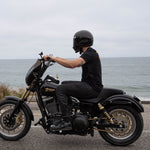 The TC Bros. Laydown License Plate Mount for Harley-Davidson features a black metal fender bracket with four screw holes and includes screws, washers, lock washers, nuts, and rubber grommets—perfect for secure mounting.