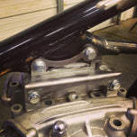 A pair of Hughs Handbuilt XS650 Top Motor Mount Window 1974-83 brackets and bolts, on a white background.