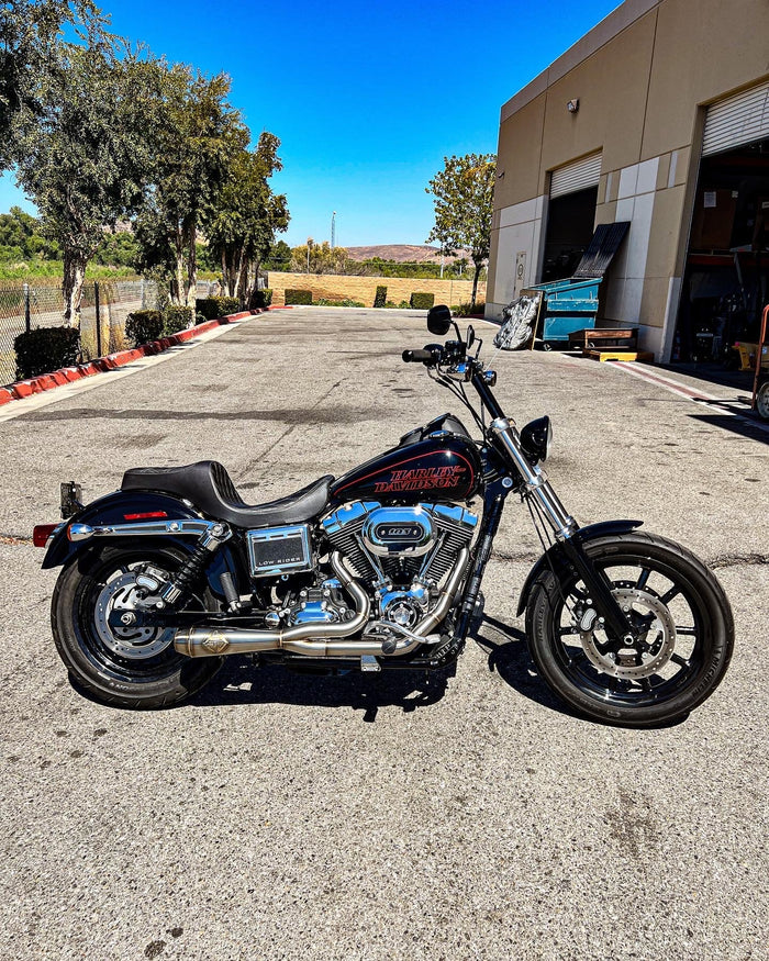 A parked motorcycle displayed its shiny SP Concepts stainless steel exhaust in the parking lot.