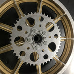 A close up of a gold motorcycle wheel with a HHB Harley Davidson Sprocket Lock System - Aluminum and bolt pattern from Hughs Handbuilt on it.