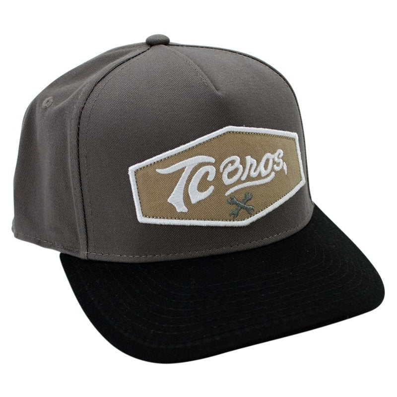 A gray and black TC Bros. Shield Snapback Hat - Charcoal/Black with a patch on it.