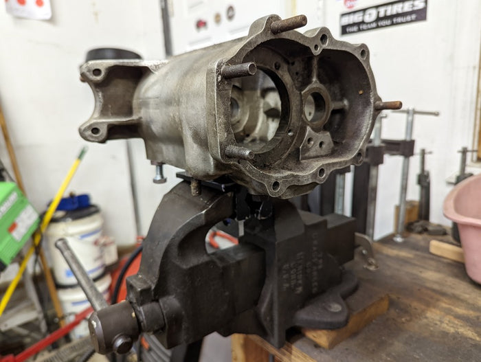 A Pangor Cycles Harley Four Speed Transmission Work Stand/Jig is sitting on a table in a workshop.