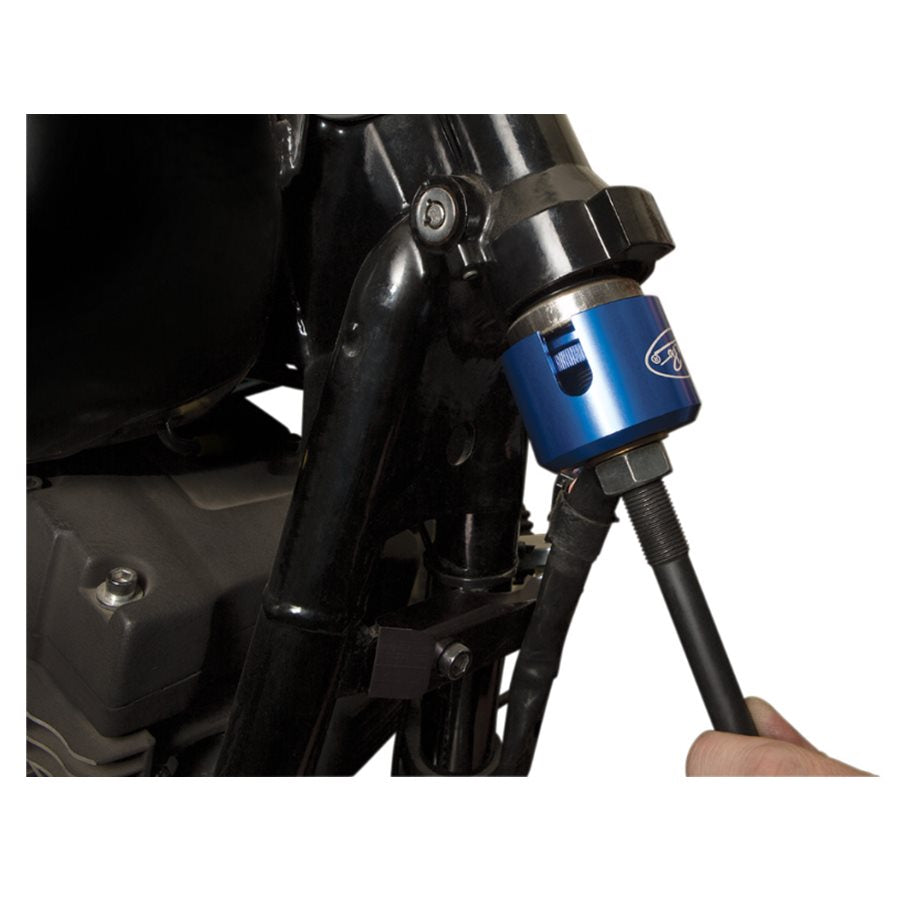 A person is using a Motion Pro Steering Bearing Race Install/Removal Tool to hold a blue hose on a Harley Davidson motorcycle.