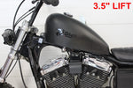TC Bros. Frisco-Style Gas Tank Lift Kit for Harley-Davidson Sportster 1995-2003, includes two black metal brackets, a black cylindrical spacer, bolt, washer, and nut—shown on a white background.