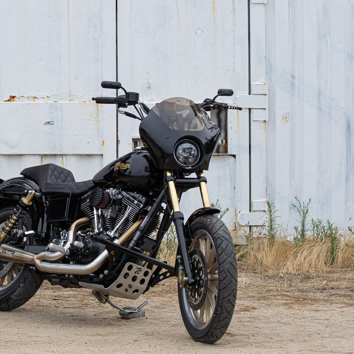 A black Harley Davidson motorcycle parked in front of a barn with a Memphis Shades Gauntlet Fairing for Narrowglide Harley front ends.