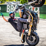 A man performing a handstand on a motorcycle, showcasing the TC Bros. 2006-2007 Harley Dyna Rear Radial Brake Bracket sportbike caliper.