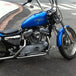 A TC Bros. Chrome Louvered Air Cleaner for S&S Super E & G Carbs with a chrome cover, a cylindrical red air filter, a black mounting bracket, three bolts, a screw, and a three-spoke wing nut are displayed, perfect for V-Twin engines.