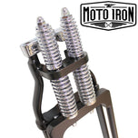 Two Moto Iron® Springer Front Ends for Harley-Davidson frames with 1" necks—one chrome, one black—are displayed side by side with a metal rod and two small parts. Ideal for custom Harley-Davidson springer setups.