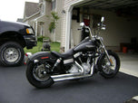 A black Burly Slammer 10.5" Shocks for Harley Davidson Dyna FXD 1991-2015 - Black motorcycle parked in front of a garage.