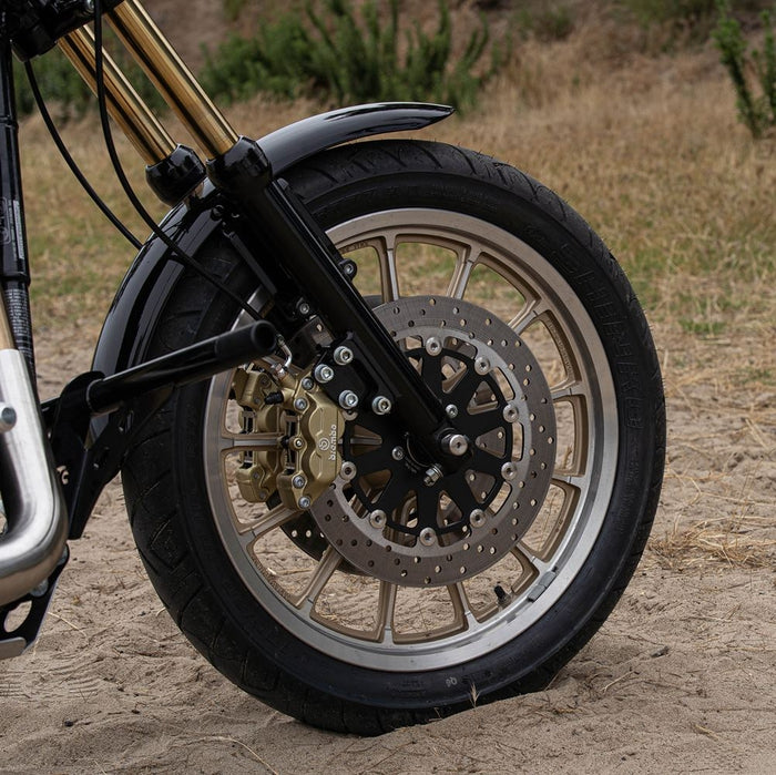 Description: A black metal bracket with three holes, similar to the TC Bros. Black Axial Brembo Front RH Bracket 2000-2017 Harley Stock Rotor, accompanied by four screws and bolts, and four washers displayed to its right.