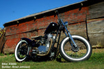 A TC Bros. 50ft Titanium Header Wrap 2 in wide (Includes locking ties) motorcycle parked in front of a barn.