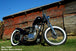 A TC Bros. 50ft Titanium Header Wrap 2 in wide (Includes locking ties) motorcycle parked in front of a barn.