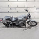 A TC Bros. Upper Shock Mount Delrin Crash Sliders 2006-2017 Harley Dyna parked in front of a garage.