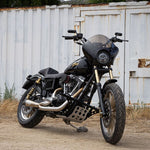 A TC Bros. Gold Titanium Nitride Coated Fork Tubes Stock Length 39mm for Sportster/ Dyna Narrow Glide motorcycle parked in front of a building.