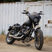 A TC Bros. Gold Titanium Nitride Coated Fork Tubes Stock Length 39mm for Sportster/ Dyna Narrow Glide motorcycle parked in front of a building.