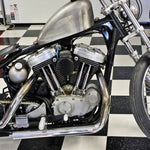 A TC Bros. Finned Black Air Cleaner S&S Super E & G Carbs vintage style motorcycle parked in a garage.