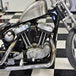 A TC Bros. Finned Black Air Cleaner S&S Super E & G Carbs vintage style motorcycle parked in a garage.