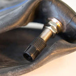 A Sedona Front Inner Tube 3.25/3.5-19 with a threaded metal valve stem attached to it.
