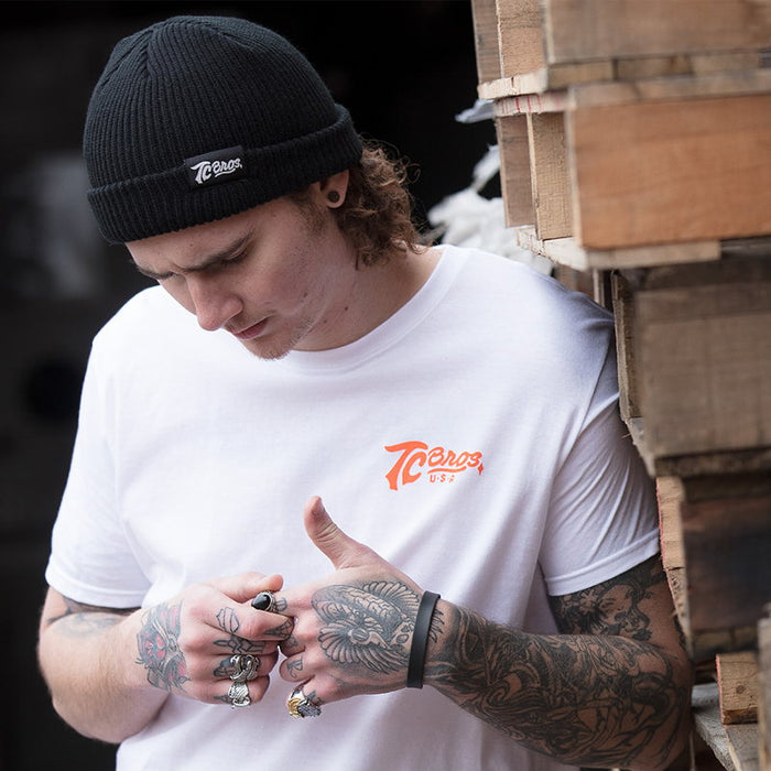 A man wearing a TC Bros. Watchman beanie - black and a white t-shirt.