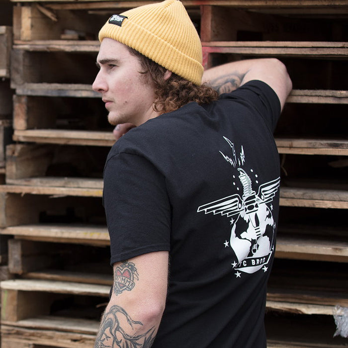 A man wearing a black t-shirt and TC Bros. Watchman Beanie - Nugget made of soft acrylic.