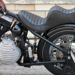 The TC Bros. Battery Box Mounting Kit for Sportster Hardtail includes a metal bracket with four slotted holes, plus bolts, nuts, and washers—perfect for securely mounting a battery box. All parts are displayed on a white background.