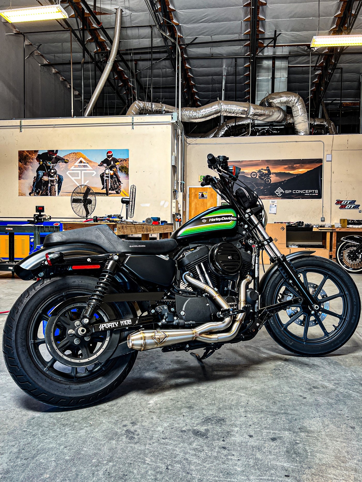 An SP Concepts Lane Splitter Exhaust Sportster 2014-2022 (stainless) motorcycle is parked in a garage.