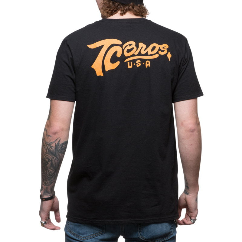 The back of a man wearing a TC Bros. Classic T-Shirt - Black with orange lettering.
