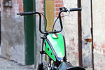 A vintage bike with Moto Iron® Vintage Style 7/8" Diameter Black Grips parked in front of a brick building.