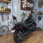TC Bros. License Plate Relocation Bracket for Harley-Davidson 2018+ Softail Street Bob and Slim, a black metal kit with mounting brackets, hardware, and logo cutout in a laydown style; shown on a white background.