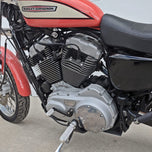 The TC Bros. Mid Controls Kit for 2004-2013 Harley-Davidson Sportster includes black brackets, silver foot pegs, bolts, nuts, washers, and a linkage rod from TC Bros., all arranged on a white background.
