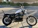A TC Bros. Extended Fork Tube Kit +4" 39mm for Sportster/ Dyna Narrow Glide with a white and black Hard Chrome Finish is parked on the sidewalk.