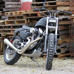 A black Shinko 805 Dual Sport Rear Tire 120/90-18 65R Bias TT motorcycle parked in front of pallets.