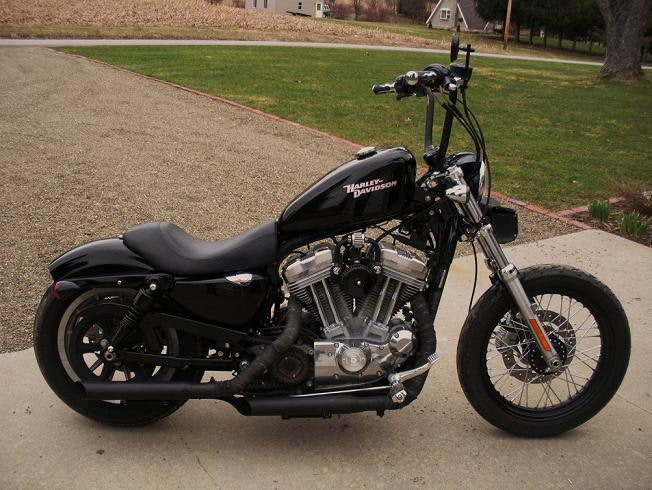 A black Burly Slammer 10.5" Shocks for Harley Davidson Sportster XL 1988-2003 motorcycle parked in front of a house.