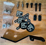 The SP Concepts Lane Splitter Exhaust for 2006-2017 Harley-Davidson Dyna features visible welds and a hexagonal logo plate, showcased on a workshop table.