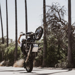 The TC Bros. Front Crash Bar for 1991-2017 Harley-Davidson Dyna is a black metal engine guard bracket with side mounts, bolts, washers, and extra metal pieces—perfect as a front crash bar for your Dyna motorcycle.
