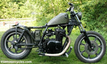A TC Bros. motorcycle parked in the grass.
